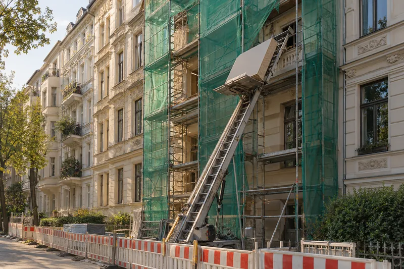 Ablauf eines Dachausbaus: Materialaufzug an einer Berliner Altbaufassade bringt Platten zum Dach